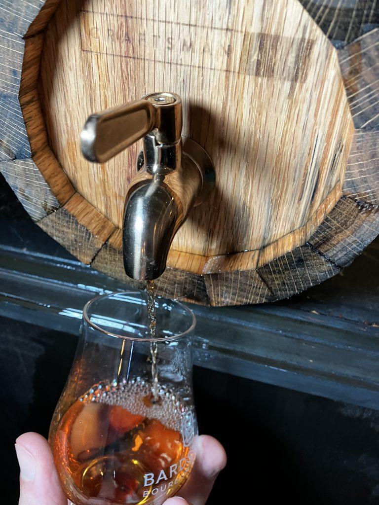 Whiskey Barrel from Craftsman Ave's Woodworking Class, Craft Your Own Whiskey Barrel, with Whiskey Being Poured into a Glass