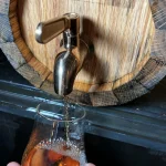 Whiskey Barrel from Craftsman Ave's Woodworking Class with Hand Pouring Whiskey into Glass