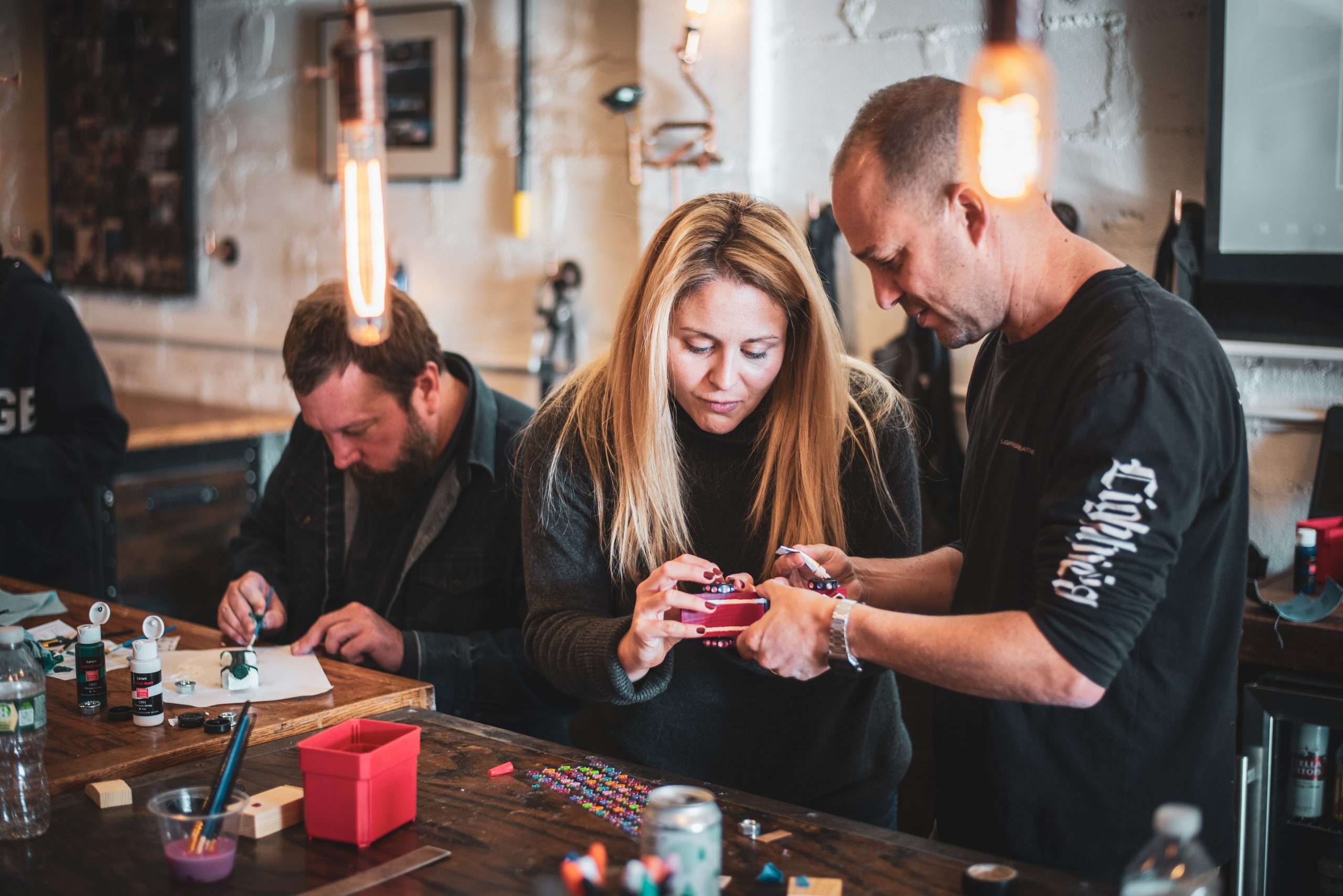 Man and woman working together on making mini race cars in Craftsman Ave's Pinewood Derby workshop