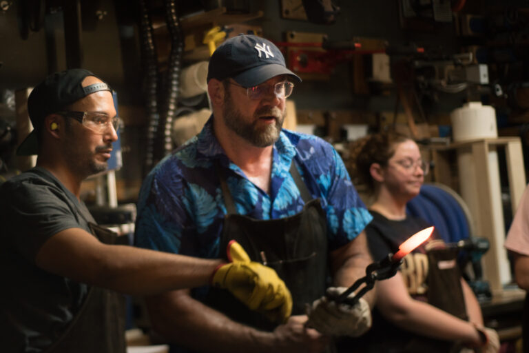 man taking out hot metal knife from forge in workshop class