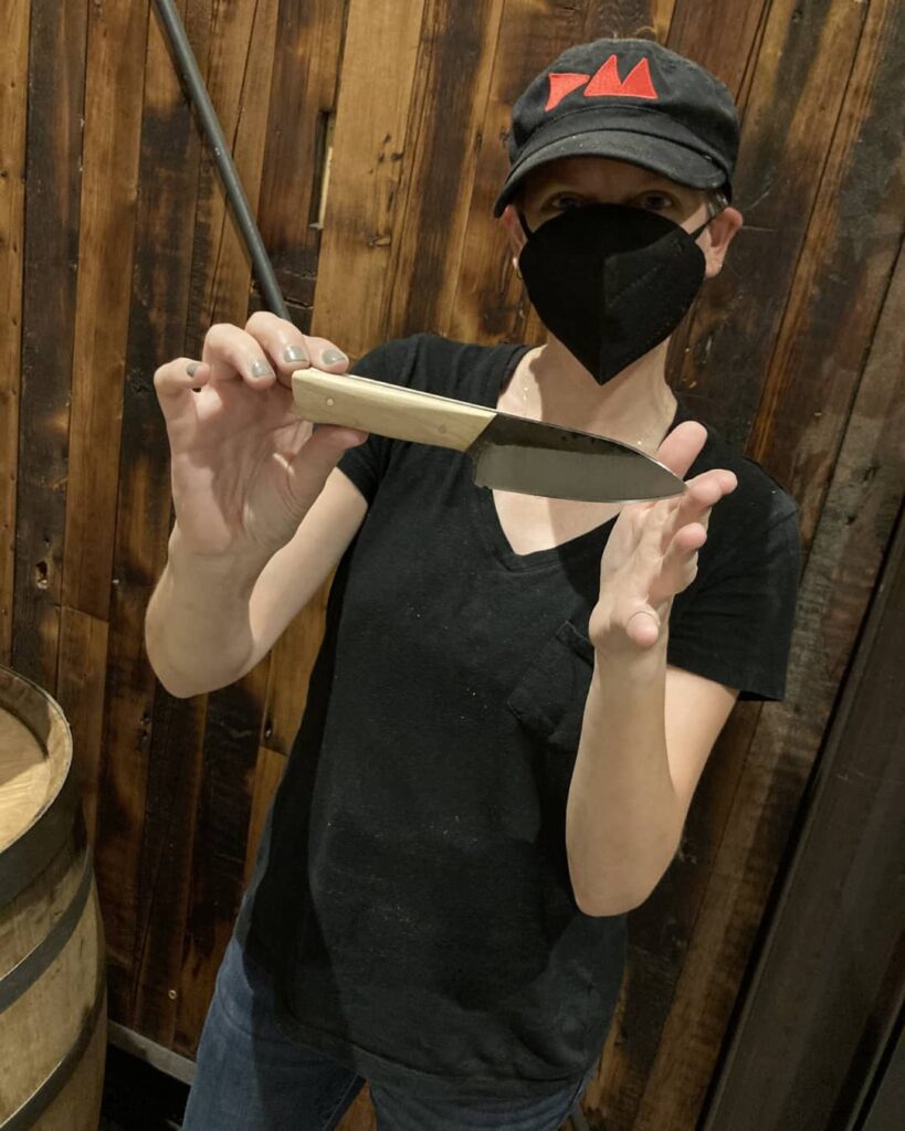 a person in a black shirt and hat holds up a knife they created