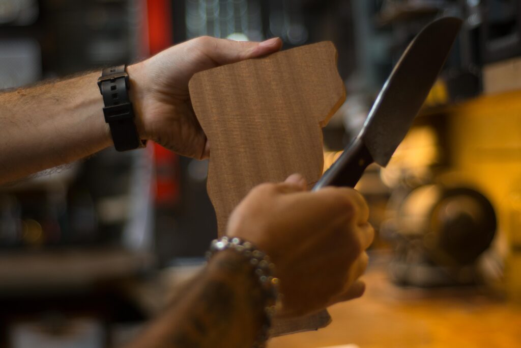 a person holds up a knife and a cutting board at a brooklyn knife making workshop